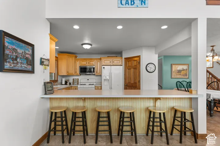 Kitchen featuring wood cabinetry, solid-surface breakfast bar, recessed lighting, and tile flooring