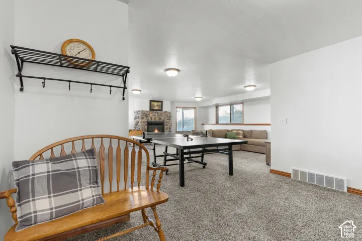 Open-concept interior featuring wall-to-wall carpeting, stone-surround fireplace, and multiple flush-mount ceiling lights