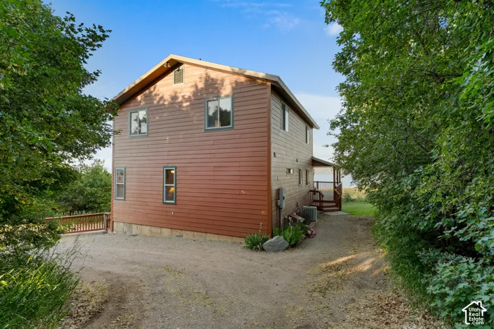 Two-story home with horizontal lap siding, gable roof, gravel driveway, and wood-railing deck