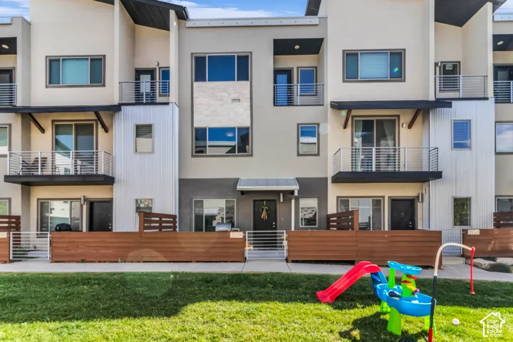 Contemporary multi-level exterior featuring metal paneling, stacked stone accents, horizontal wood-slat fencing, and elevated steel-railing balconies