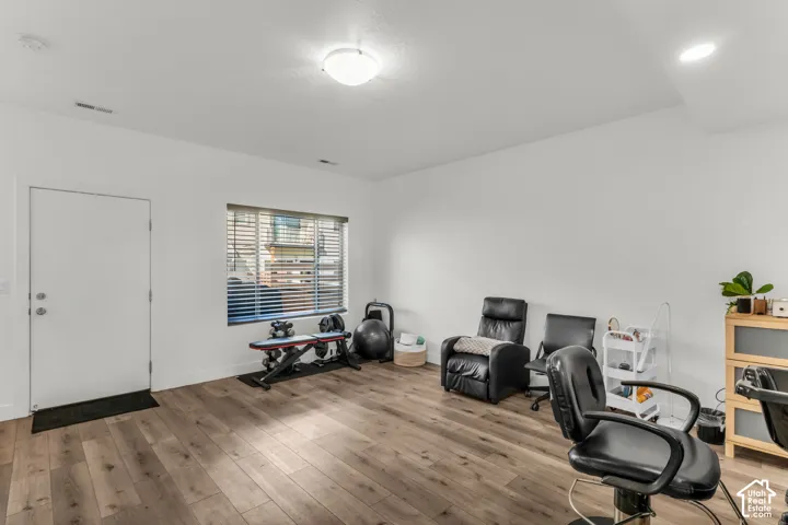 Interior room featuring wood-finish flooring, white walls, a flush-mount ceiling light, and a single-panel door