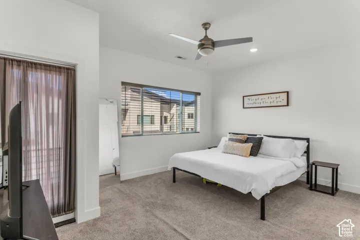 Neutral-toned carpeting, ceiling fan with integrated lighting, recessed lighting, and large window with horizontal blinds