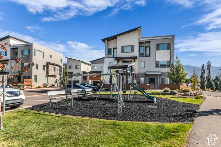 Contemporary multi-story exterior featuring a mix of stucco and stone-accent siding, shed-style rooflines, private balconies, and hardscaped community playground area