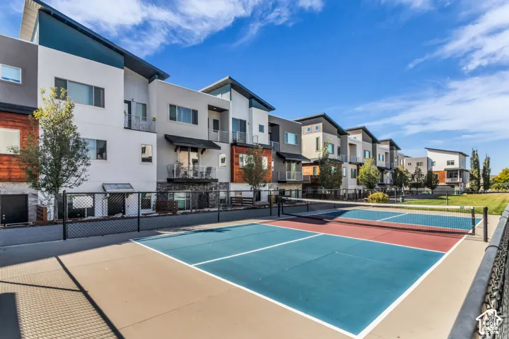 Multi-level exterior featuring a combination of stucco and wood-finish siding, metal roof lines, metal railings, and a hardscaped pickleball court