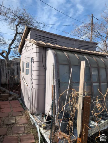 Structural outbuilding featuring a curved polycarbonate roof panel system, arched dual windows, integrated ventilation louvers, and molded exterior siding, situated on a stone paver path