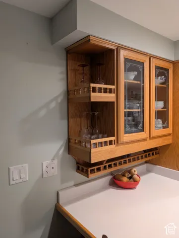 Built-in oak cabinetry featuring glass-front doors with decorative etching, open-shelf display units, and an integrated spindle-rail rack