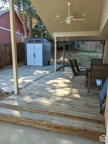 Covered wooden deck featuring a ceiling-mounted fan, recessed lighting, and a fenced backyard area