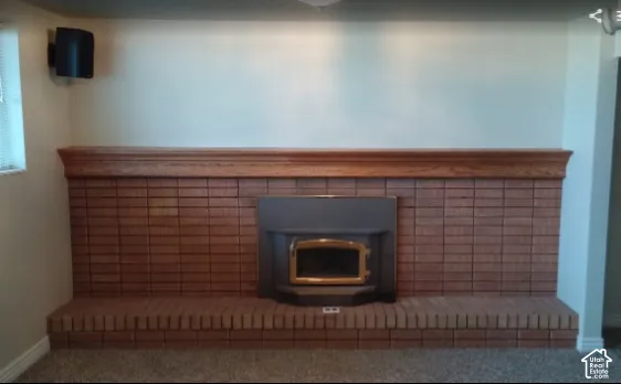 Floor-to-ceiling brick fireplace surround featuring an elevated brick hearth, a wood-finish mantel, and an integrated metal fireplace insert