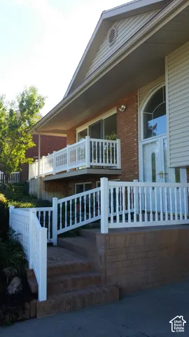 Exterior facade featuring brick masonry and horizontal siding, elevated brick staircase, white picket-style railings, and a multi-pane arched glass front door