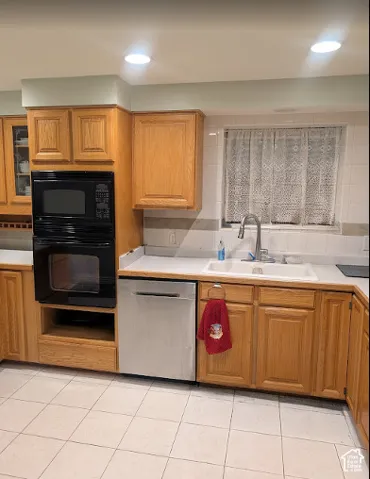 Kitchen featuring oak cabinetry, a built-in double wall oven, stainless steel dishwasher, white tile backsplash, and ceramic tile flooring