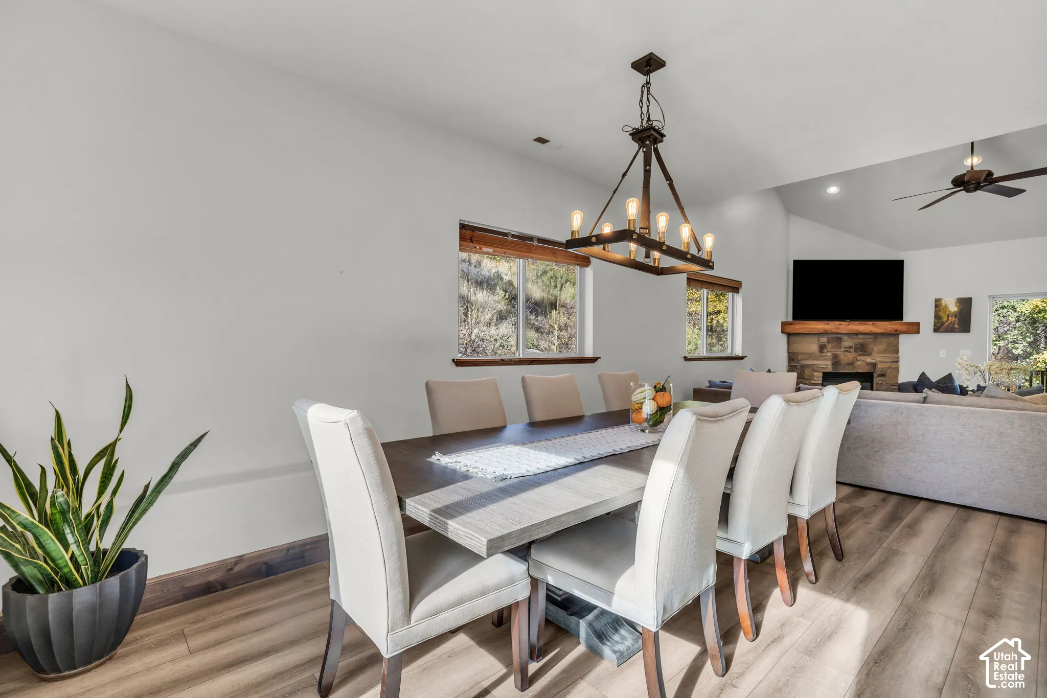 Elegant dining area showcasing a wood-finish dining table with upholstered chairs, hardwood flooring, and a striking wood and metal pendant chandelier