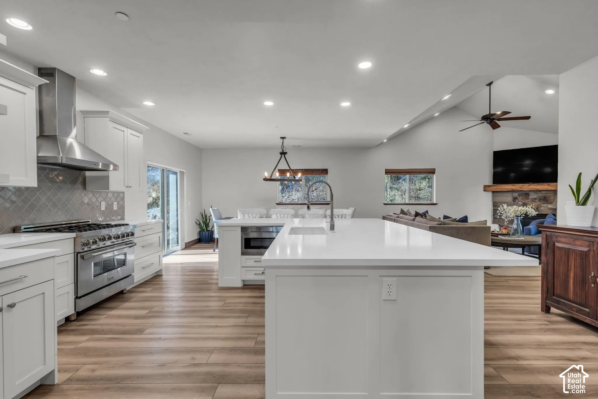 Kitchen featuring a large central island, stainless steel appliances, white cabinetry, and wood-finish flooring