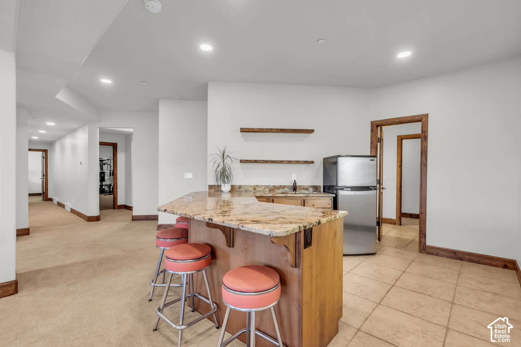 Built-in bar with wood cabinetry, granite-style countertop, and stainless steel refrigerator