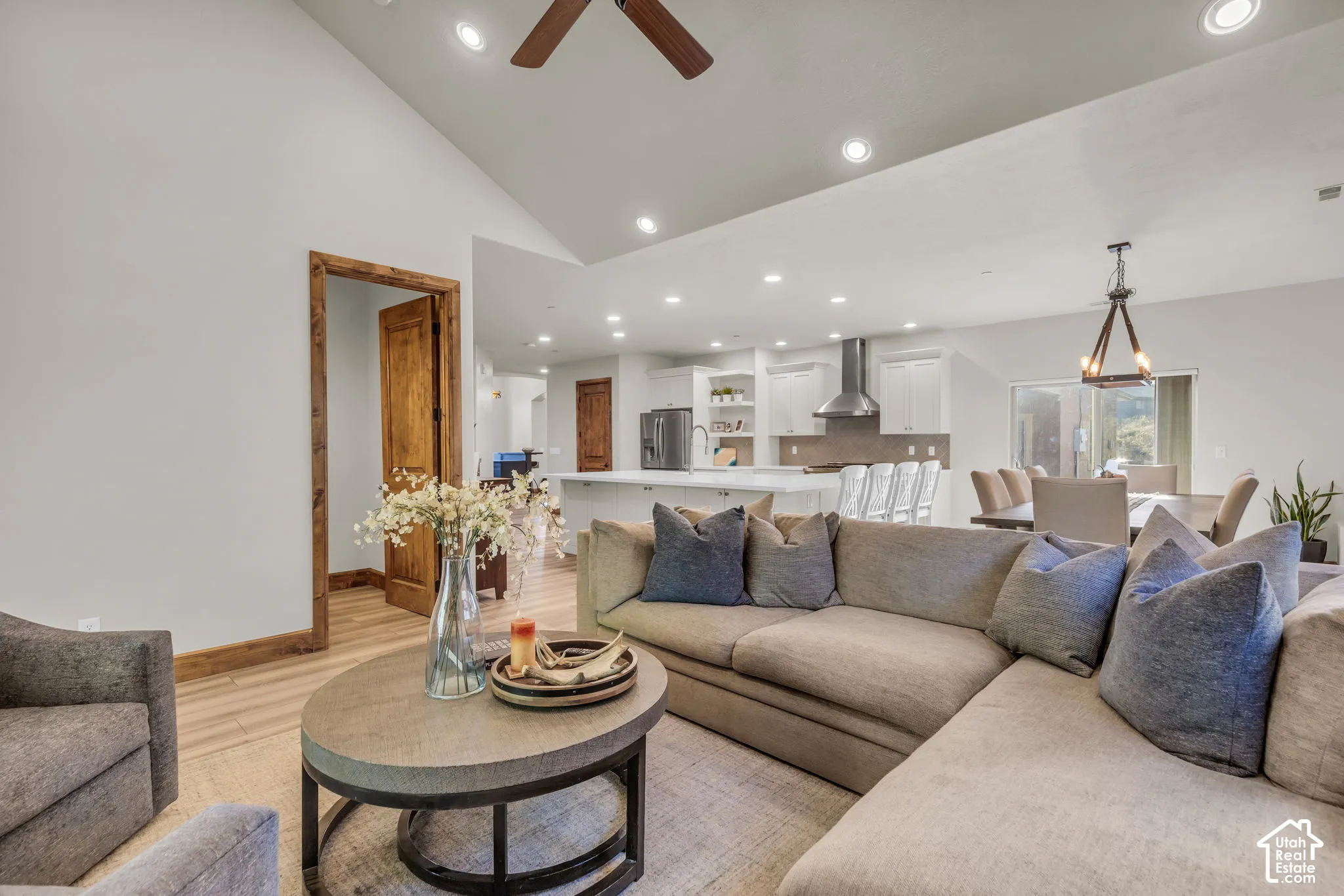 Vaulted ceiling, recessed lighting, wood-finish flooring, white cabinetry, and stainless steel appliances
