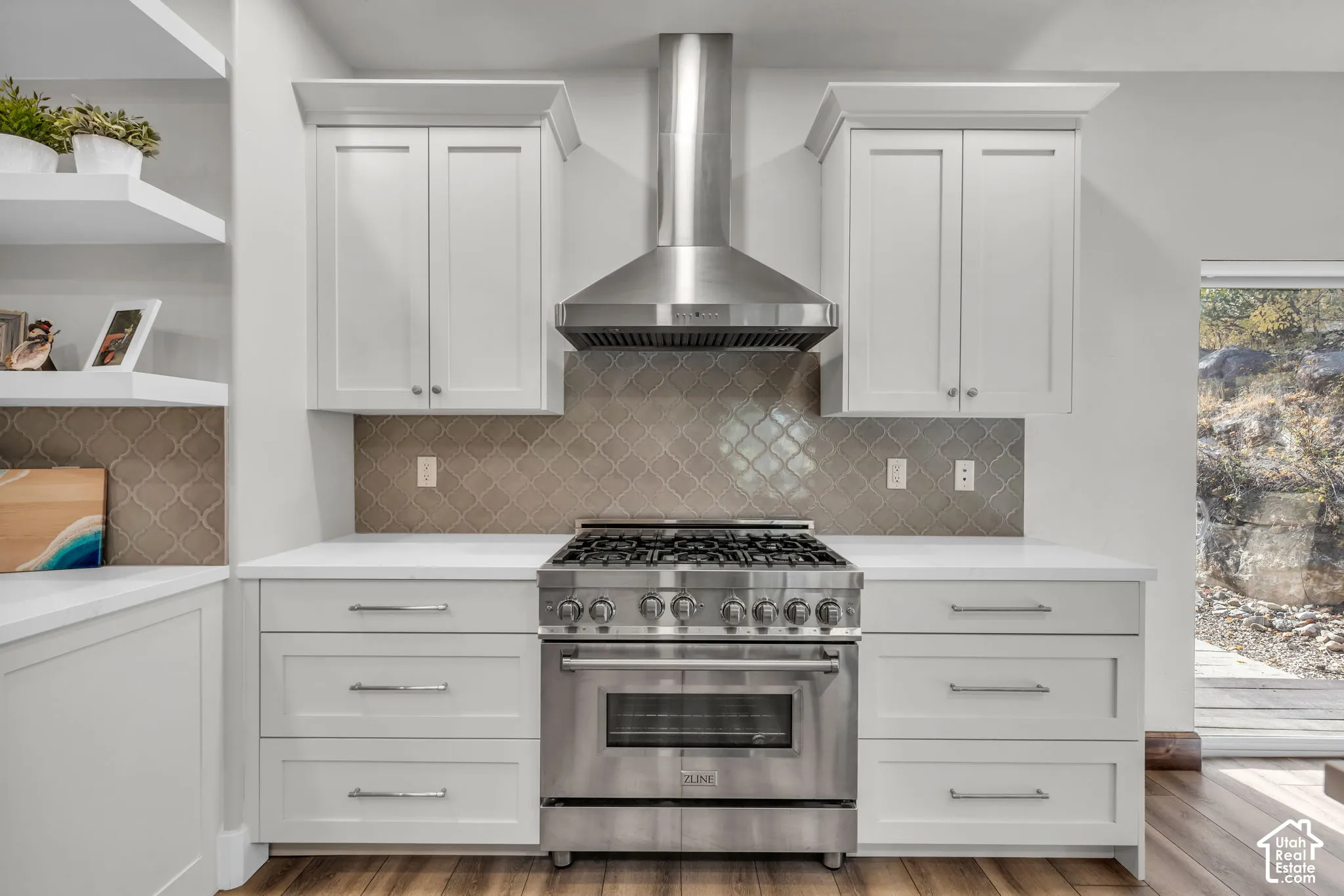 Chef's kitchen showcasing custom white cabinetry, professional-grade stainless steel range with six burners and convection oven, stainless steel range hood, quartz countertops, and geometric tile backsplash