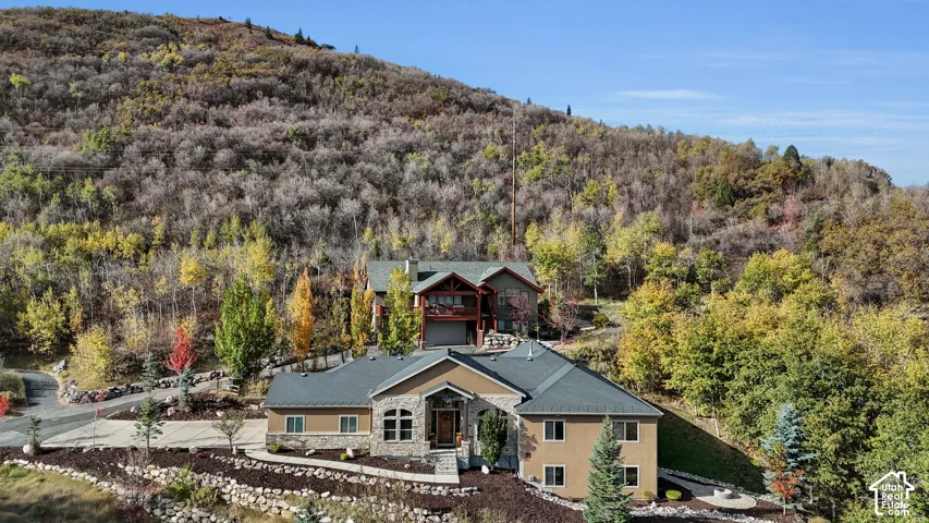Terraced landscaping with stone retaining walls, mature trees, and a paved driveway