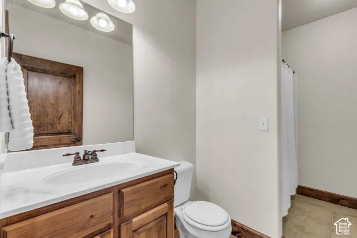 Bathroom featuring a wood-finish vanity with a white countertop, an undermount sink, and a bronze-finish faucet
