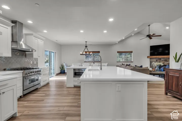 Kitchen featuring a large central island, stainless steel appliances, white cabinetry, and wood-finish flooring