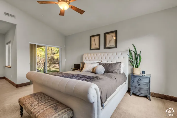 Vaulted ceiling, ceiling fan, sliding glass door, private balcony with metal railing, and carpeted flooring