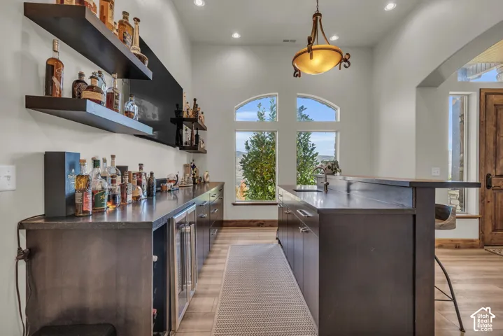 Built-in wet bar with wood-finish cabinetry, under-counter beverage refrigerators, and floating shelves