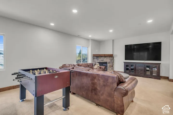 Spacious living area featuring a stone-clad fireplace with wood mantle, recessed lighting, and expansive windows