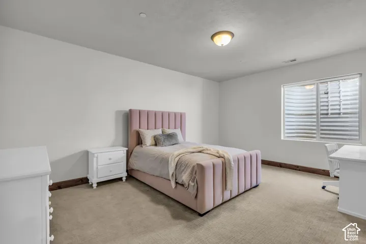 White-painted walls with light-colored carpeting, featuring a window with a well-cover