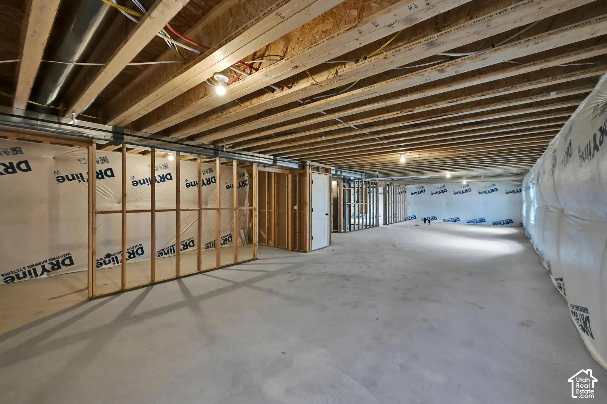Unfinished interior space featuring exposed wood-joist ceiling, concrete flooring, and framed wall partitions with vapor barrier insulation