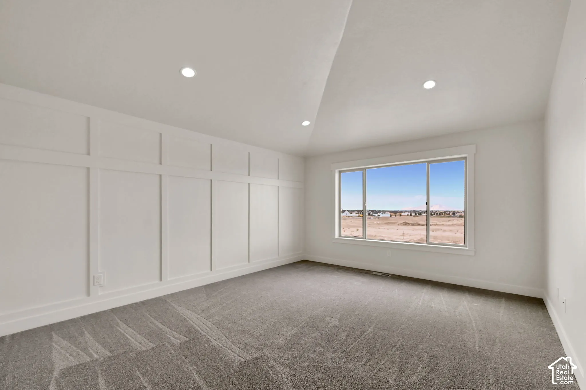 Vaulted ceiling featuring recessed lighting, extensive board-and-batten wall detailing, and a large horizontal window