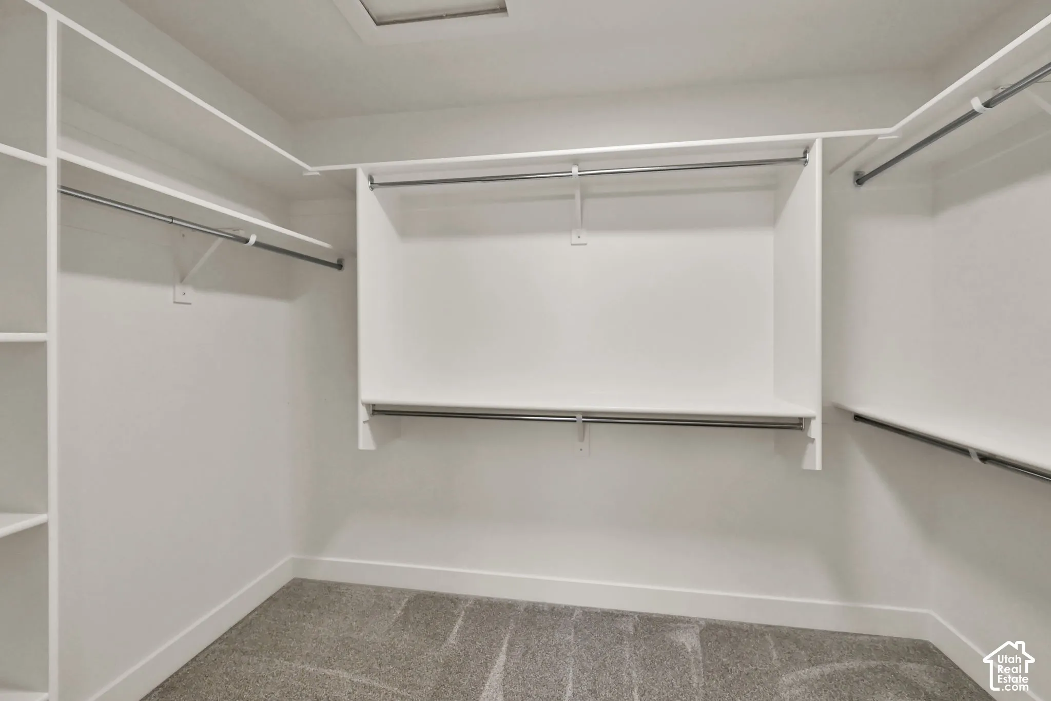 Walk-in closet featuring white custom shelving, tiered hanging rods, integrated storage cubbies, and carpeted flooring