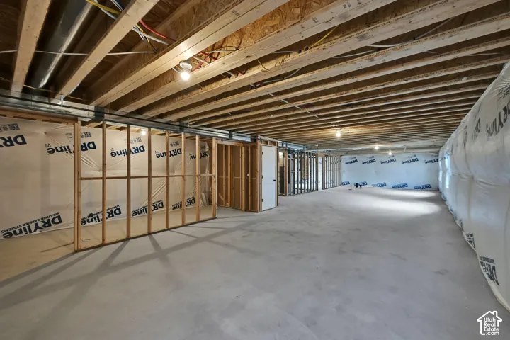 Unfinished interior space featuring exposed wood-joist ceiling, concrete flooring, and framed wall partitions with vapor barrier insulation