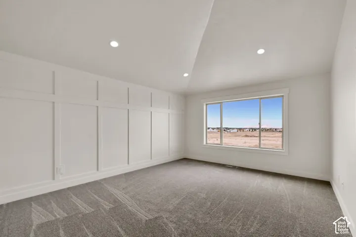 Vaulted ceiling featuring recessed lighting, extensive board-and-batten wall detailing, and a large horizontal window