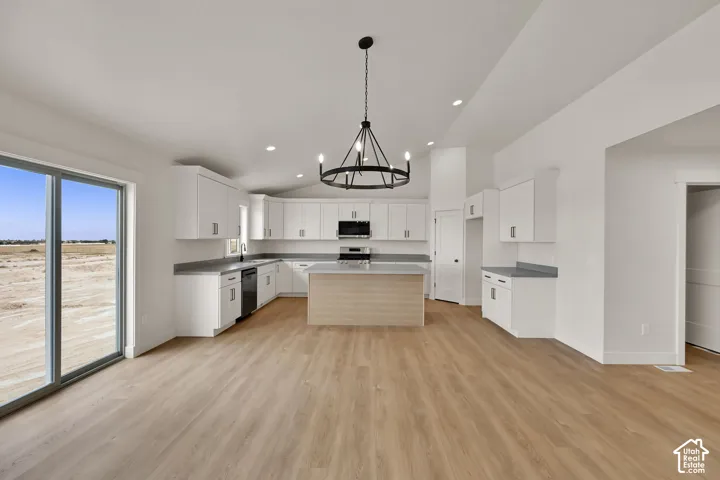 Kitchen featuring white cabinetry, solid-surface countertops, central island, wood-finish flooring, and a multi-arm chandelier