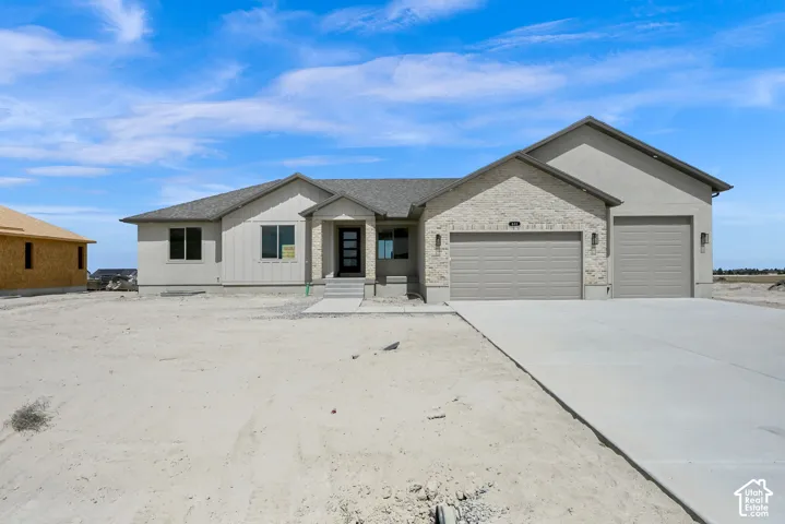 Exterior featuring a mixed-material facade of stone veneer and vertical siding, a three-car garage, a concrete driveway, and a covered front entry