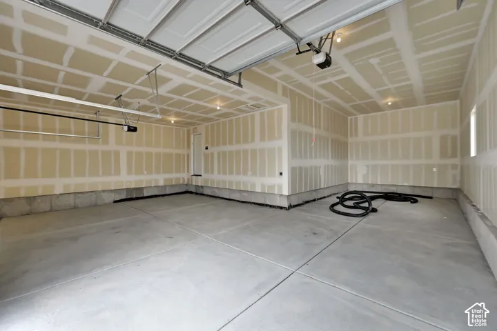 Multi-car garage featuring a concrete floor, finished drywall, ceiling-mounted automatic door openers, and recessed lighting