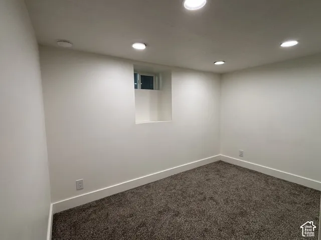 Recessed lighting, neutral wall paint, window well, new carpet, and clean trim