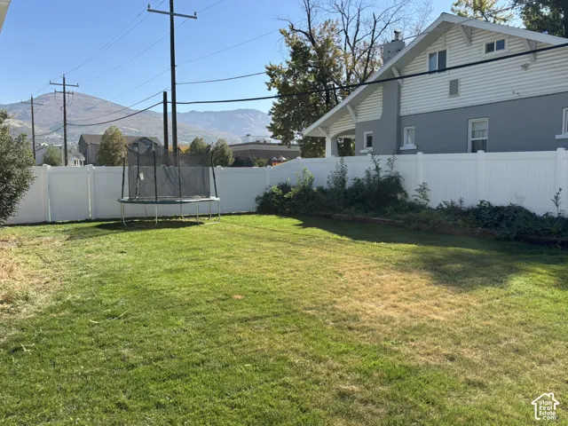 Expansive grassy yard with white privacy fencing and mountain scenery