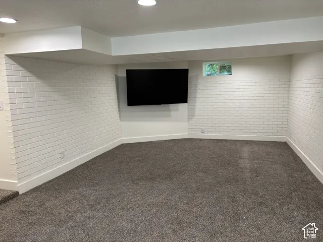 Recessed lighting illuminating a spacious room with white painted brick accents