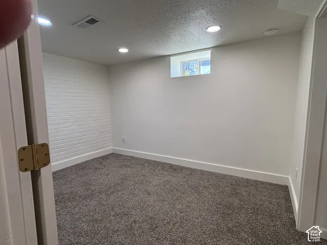 Textured accent wall, recessed lighting, carpet flooring, window, and white trim