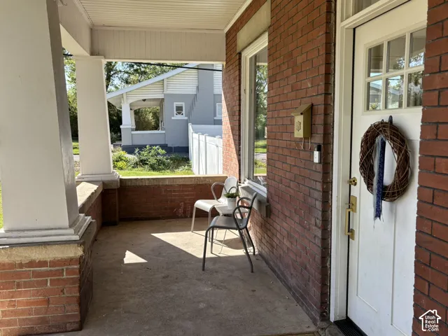 Brick exterior featuring a covered concrete porch with white columns