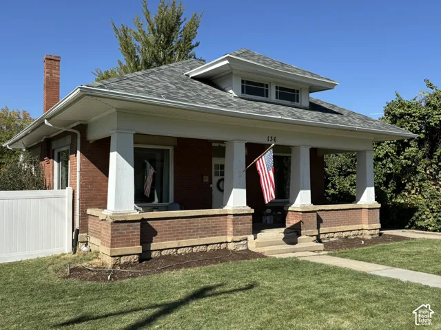 Brick exterior with a covered porch, white columns, and a stone foundation