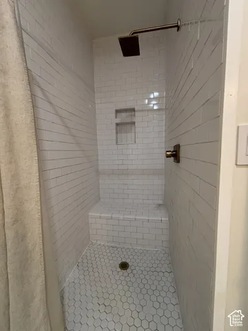 Shower with subway tile walls, hexagon tile flooring, a built-in bench, and a recessed niche