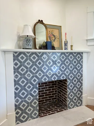 Fireplace featuring decorative blue and white tile surround, a white mantel, and a brick firebox