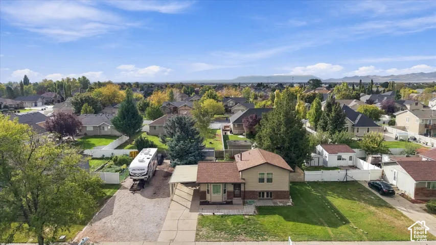 Exterior property featuring a shingled roof, brick and siding facade, covered carport, and expansive lot with mountain scenery