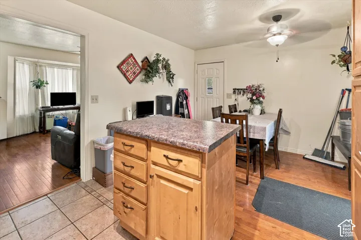 Kitchen featuring a center island with wood cabinetry, tile flooring, wood-finish flooring, and a ceiling fan with integrated lighting