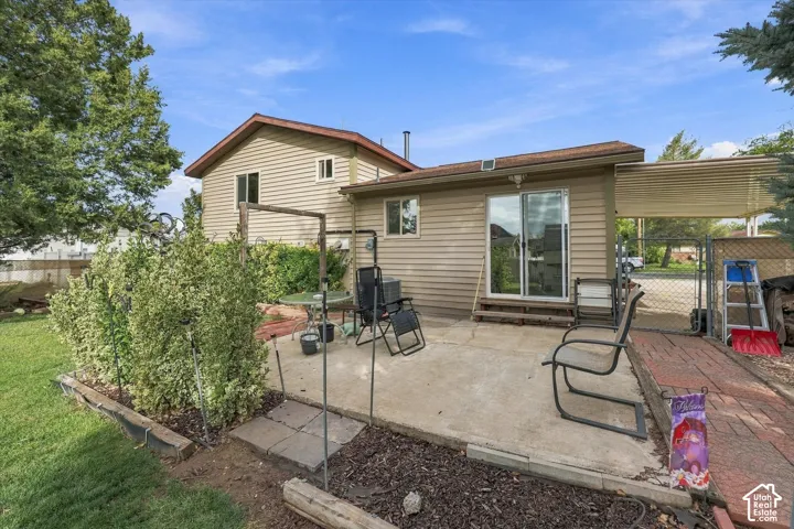 Exterior view featuring horizontal siding, a concrete patio, a covered carport, and a brick-paved walkway