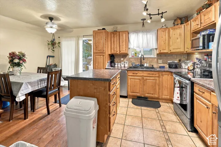 Kitchen featuring wood cabinetry, a center island with countertop, tile flooring, and track lighting
