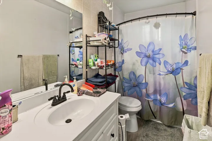 Bathroom featuring a white vanity cabinet with a solid surface countertop, an oval undermount sink, a matte black faucet, and a large wall-mounted mirror