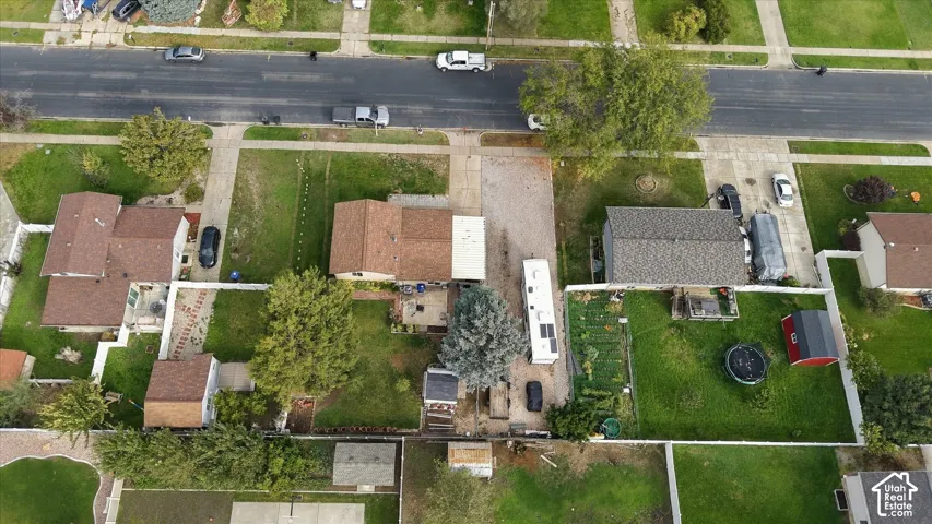 Aerial perspective of a property featuring an expansive backyard, a detached storage structure, mature trees, and a long gravel driveway