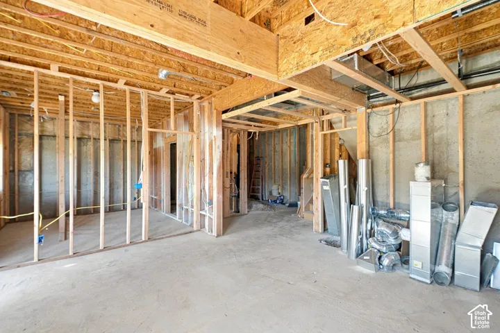 Unfinished interior space featuring exposed wood-stud framing, exposed structural joists, concrete flooring, and installed metal HVAC ductwork