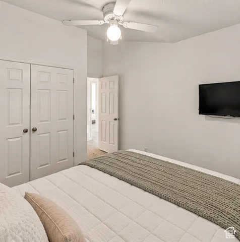 Vaulted ceiling with white ceiling fan and light fixture, dual-panel closet doors, and interior paneled door